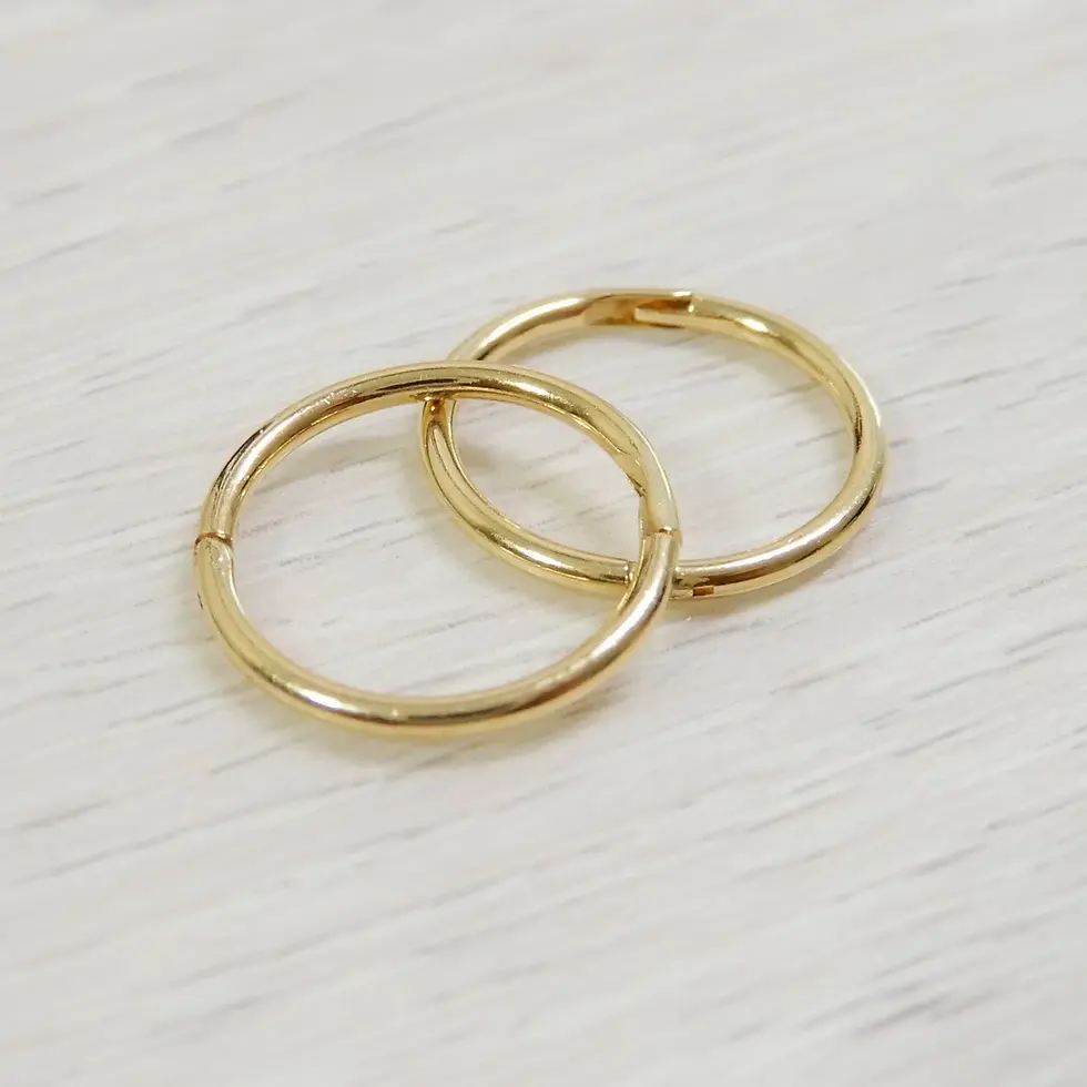 Pair of polished 10mm yellow gold sleeper hoops on wood background