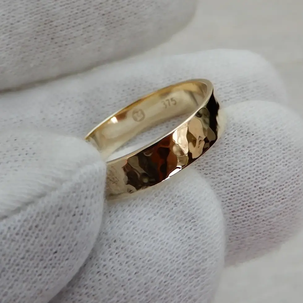 Thumbnail: Polished hammered finish yellow gold wedding band displayed close-up in glove
