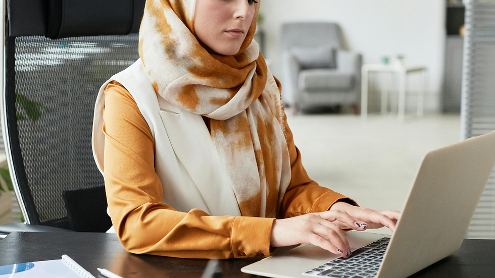 Woman, wearing a headscarf, working independently on a laptop at a desk, representing focused support in entrepreneurship, with The Heart of Finance logo
