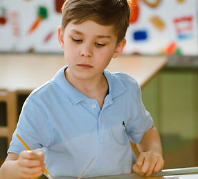a young boy concentrating on an activity at kinder