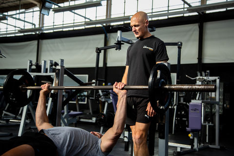 Two male models, showcasing The Empowered Man's online fitness coaching transformation program in a high-quality photo shoot by Jamie Bulman. The models are seen working out and flexing their muscles while wearing The Empowered Man apparel, promoting the 8-week transformation program. The photo shoot helped increase sales by 2000%.
