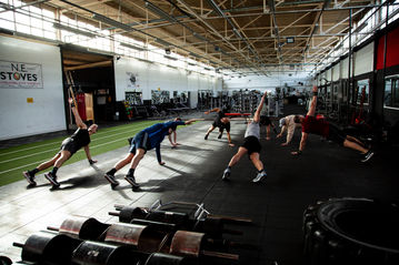 Two male models, showcasing The Empowered Man's online fitness coaching transformation program in a high-quality photo shoot by Jamie Bulman. The models are seen working out and flexing their muscles while wearing The Empowered Man apparel, promoting the 8-week transformation program. The photo shoot helped increase sales by 2000%.