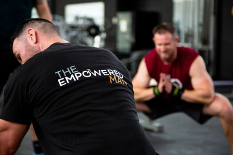 Two male models, showcasing The Empowered Man's online fitness coaching transformation program in a high-quality photo shoot by Jamie Bulman. The models are seen working out and flexing their muscles while wearing The Empowered Man apparel, promoting the 8-week transformation program. The photo shoot helped increase sales by 2000%.
