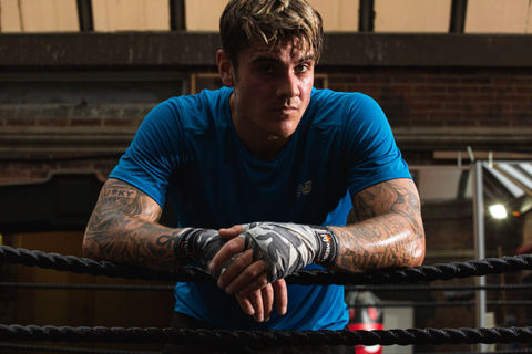 The photo on the website is from a high-quality photoshoot by Jamie Bulman featuring Luke Mabbott from Love Island. Luke is seen promoting gym clothing for BoohooMAN clothing in a boxing ring. The photo shoot has increased engagement by 350% and is being used to promote the clothing line.