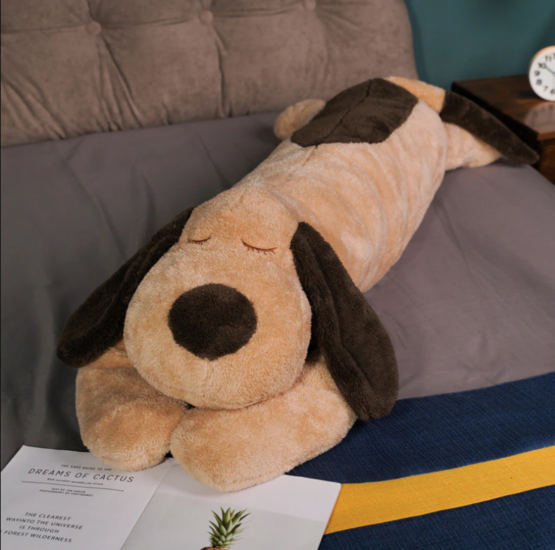 Large plush dog laying on bed, sleeping. Giant Sleeping Plush Dog Hug Pillow-for Sensory Comfort.