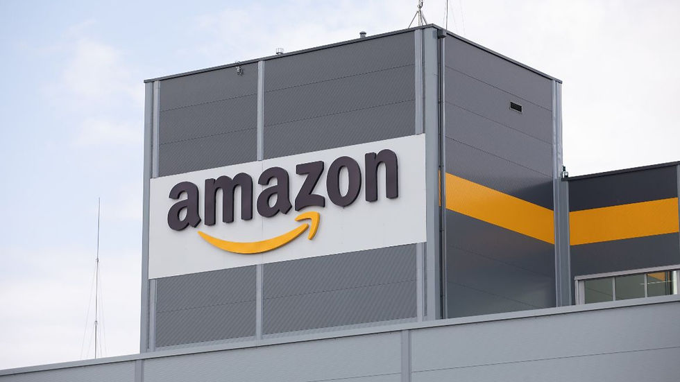 Amazon logo on a gray building with a yellow stripe, set against a cloudy sky, conveying a corporate and modern atmosphere.