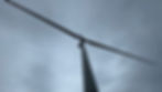 Looking up at a tall wind turbine against a cloudy sky. The turbine blades stretch wide, creating a dynamic, industrial mood.