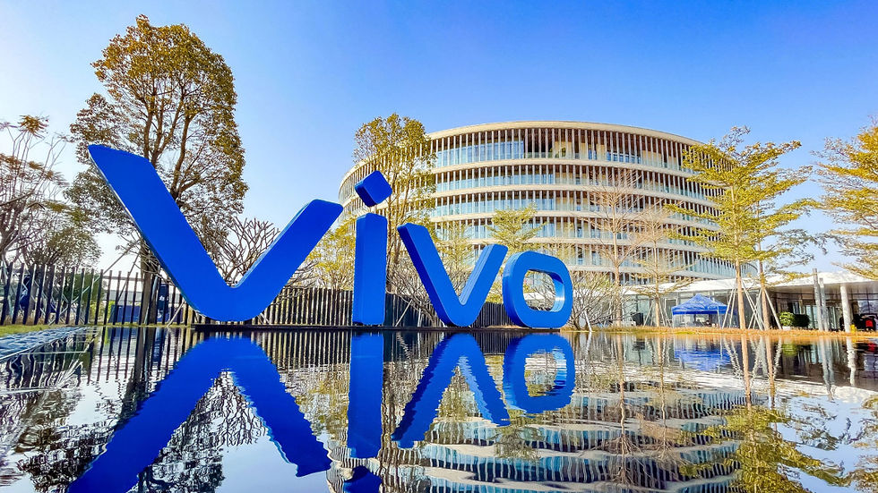 A large blue "Vivo" sign in front of a modern, circular building surrounded by trees, reflected in a pool of water under a clear blue sky.