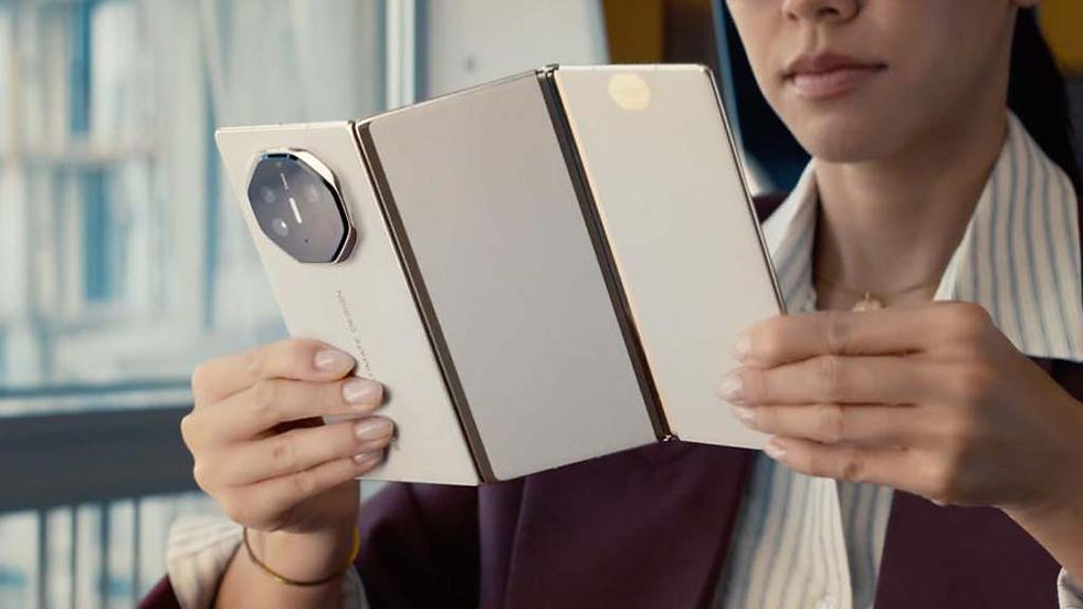 Woman holds and examines a folded white device with a camera, set in a bright room. She looks focused and the device has visible hinge detail.