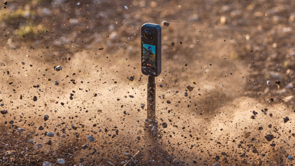 A camera on a monopod amidst a cloud of flying dirt and rocks, capturing dynamic outdoor action. Brown earthy background.