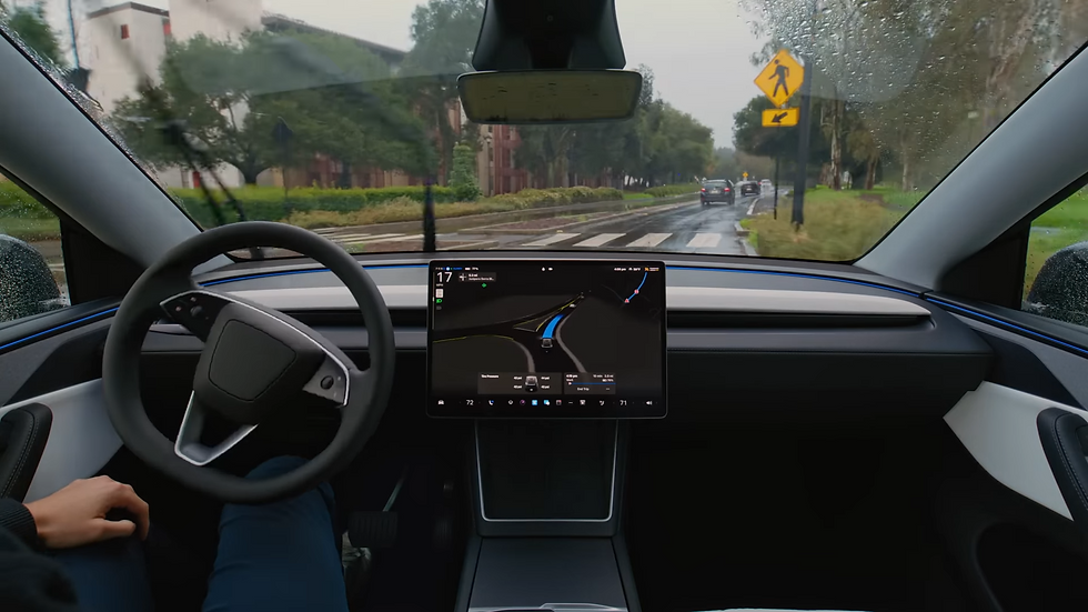 Car interior with a visible steering wheel and central screen displaying a map. It's rainy outside, with trees and a crosswalk visible.