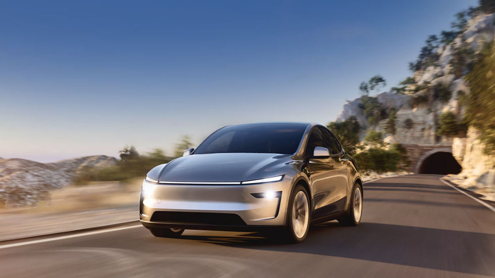 Silver car driving on a scenic mountain road with a tunnel in the background. Clear blue sky, suggesting a calm, sunny day.