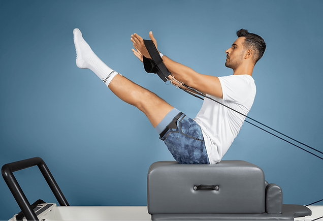 Lead instructor, Arda, in a reformer pilates pose, glide straps in hand.