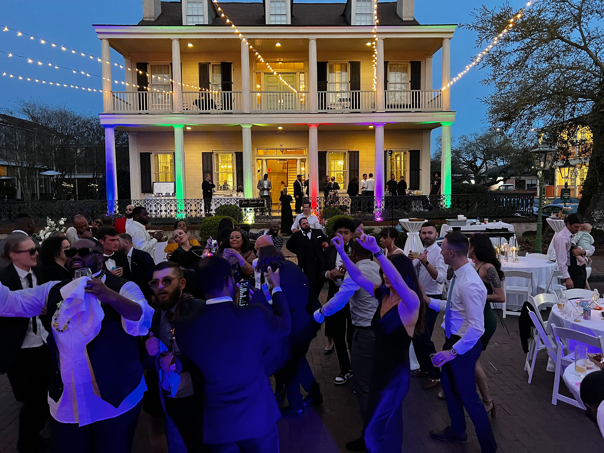 Wedding reception with colorful uplighting illuminating a historic venue exterior in Mobile, AL