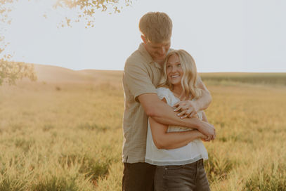 Couple embracing in a golden field at sunset, Northwest Iowa engagement photos
