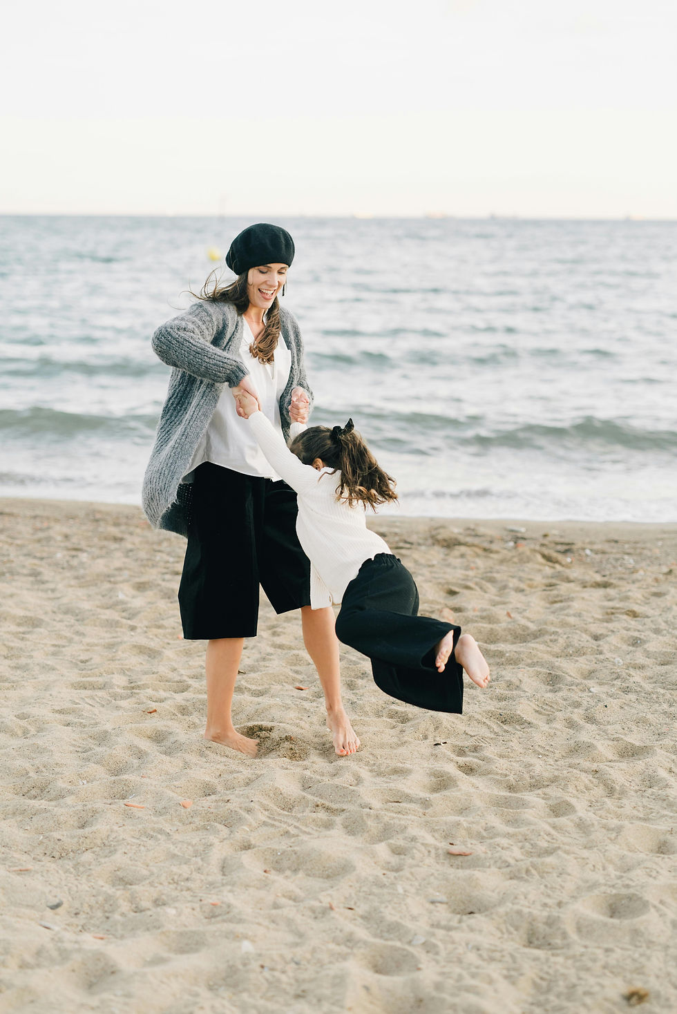 Une mer et sa fille en train de danser sur une plage de sable