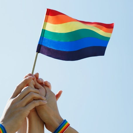 Parents holding their child's hand with a pride flag