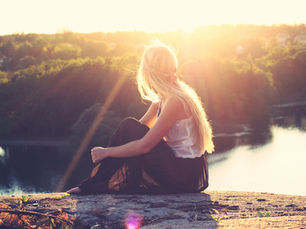 A woman contemplating by a calm lake. 