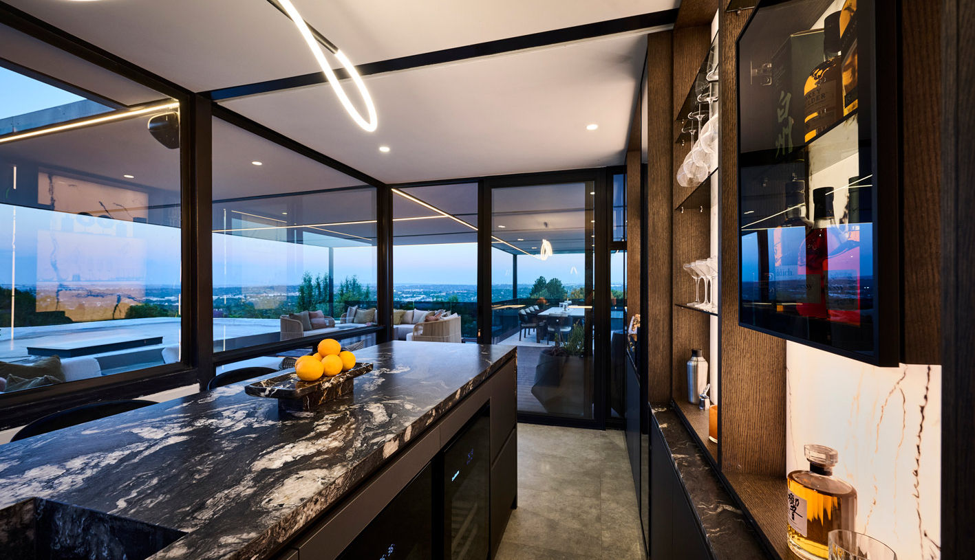 Contemporary home bar with floor-to-ceiling windows offering a panoramic outdoor view, highlighting the contrast between the dark interior finishes and the bright exterior.
