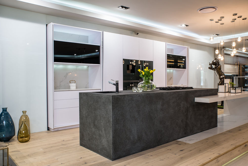 Modern kitchen with sleek black island, white cabinets, and wood floor. Yellow tulips in a vase. Pendant lights and abstract statue adorn.