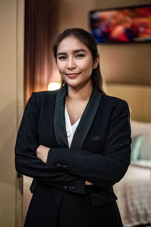 property agent, dressed in a formal suit, showcasing a unit behind her.