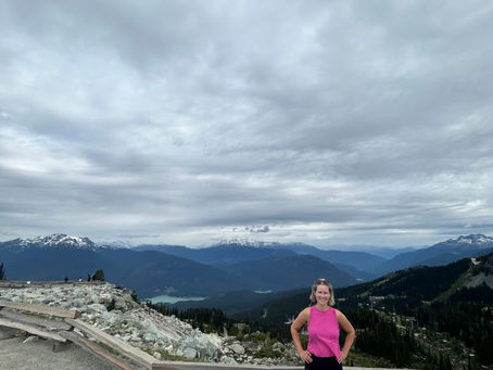 woman on backcomb summit with mountain views behind her