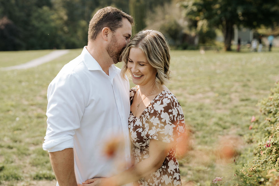 Man in dress shirt kissing head of woman in floral dress in a summer field