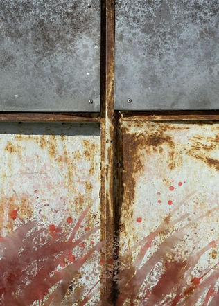 Close-up of weathered metal with red and white paint splatter background.