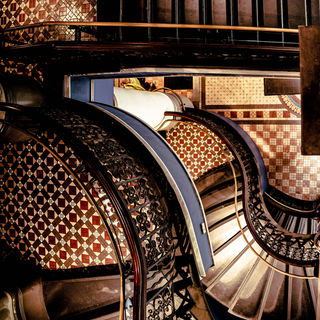Ornate staircase with patterned tiles and railing, architectural detail.