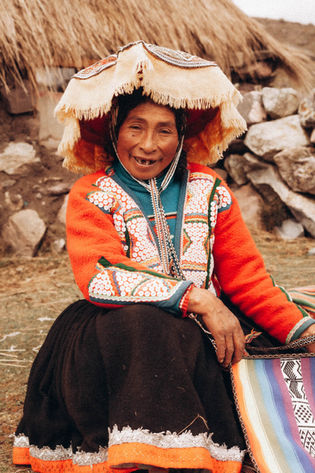 Smiling woman in traditional attire, smiling, posing in front of mountains.