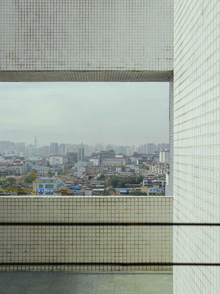 View of a city from a building window with an overcast sky.