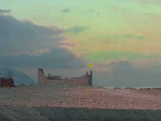 Ruined building silhouette against the sunset sky over the desert landscape.