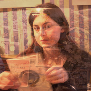 A woman's pensive expression is overlaid with a collage of vintage posters and photographs, creating a layered, introspective and nostalgic tone.