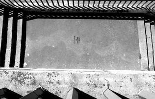 High-angle shot, concrete surface, with shadows and a building's edge.
