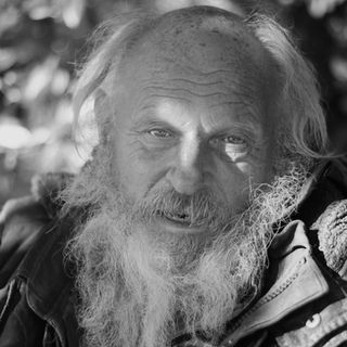 Elderly man with long white beard in black and white portrait.