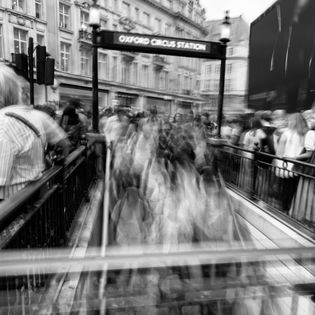 Blurred figures entering Oxford Circus Station in London, England. People moving fast.