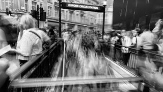 Blurred figures entering Oxford Circus Station in London, England. People moving fast.