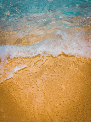 Ocean waves washing ashore on golden sand beach, turquoise water.