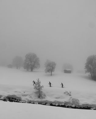Black and white photograph of individuals in snowy conditions, showcasing their energy against a winter backdrop.