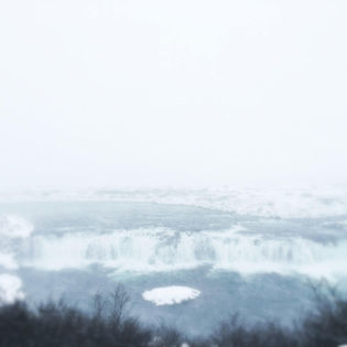 A stunning view of a waterfall cascading down rocky cliffs, surrounded by mist.