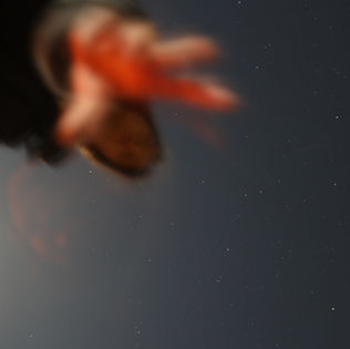 A blurred hand reaching out against a starry night sky.