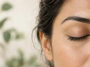 Close-up of a natural eyebrow and closed eye in soft daylight; AI-generated editorial illustration.