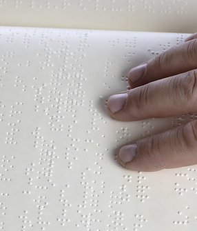 A hand touching a braille document