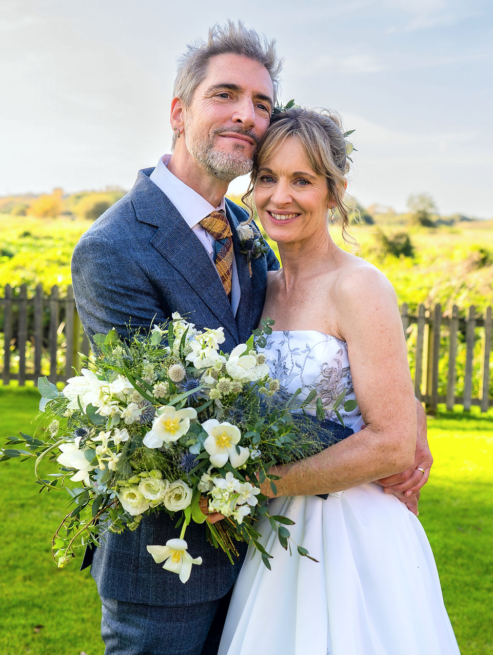Wedding portrait of bride, groom and flowers on sunny day