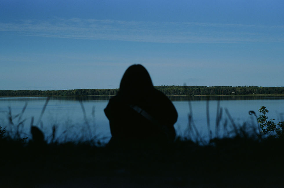 Silhouette of a person sitting peacefully by a lake
