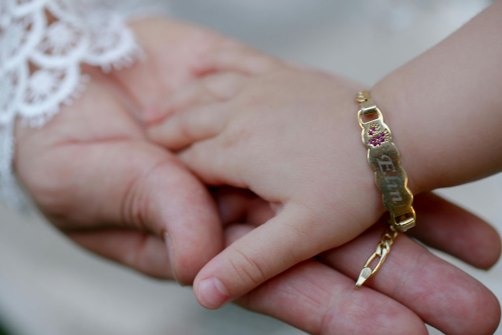 Baby hand with name bracelet in larger adult hand