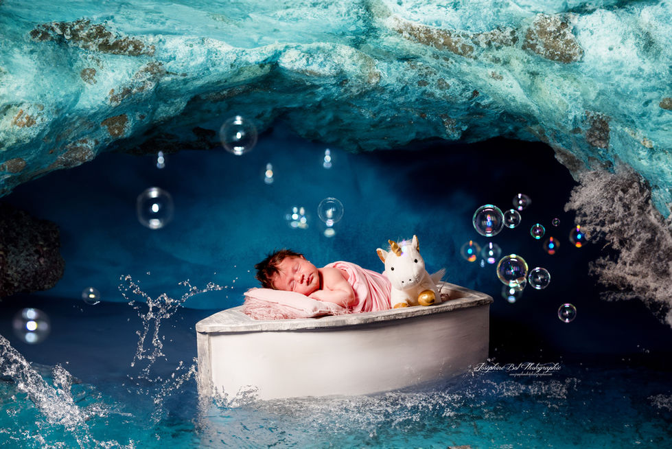 Bébé dort paisiblement dans un petit bateau blanc, entouré de bulles.Joséphine Bot photographe Ariège