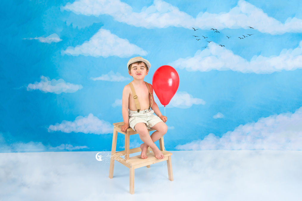Arthur Petit garçon souriant avec un ballon rouge et devant un ciel bleu. Enfant, Joséphine Bot photographe Ariège