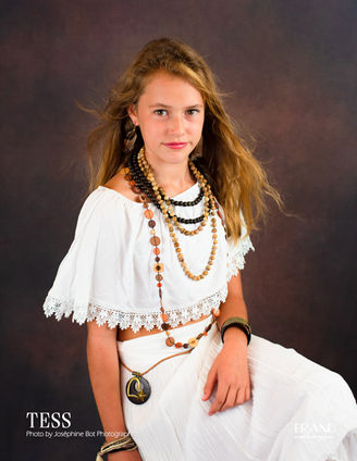 Jeune fille nommée Tess, vêtue d'une robe blanche, pose pour une photo studio.