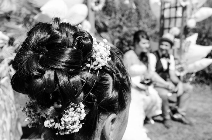 Coiffure ornée de fleurs, Mariage, couple souriant en arrière-plan. Joséphine Bot photographe Ariège.